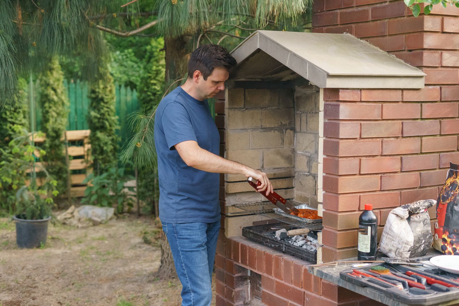 Barbecueën aan een gemetselde buitenkeuken in de tuin